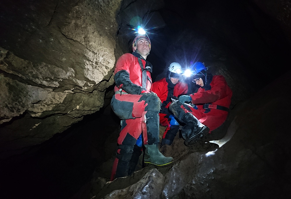 kolme luolailijaa lukee karttaa luolasa